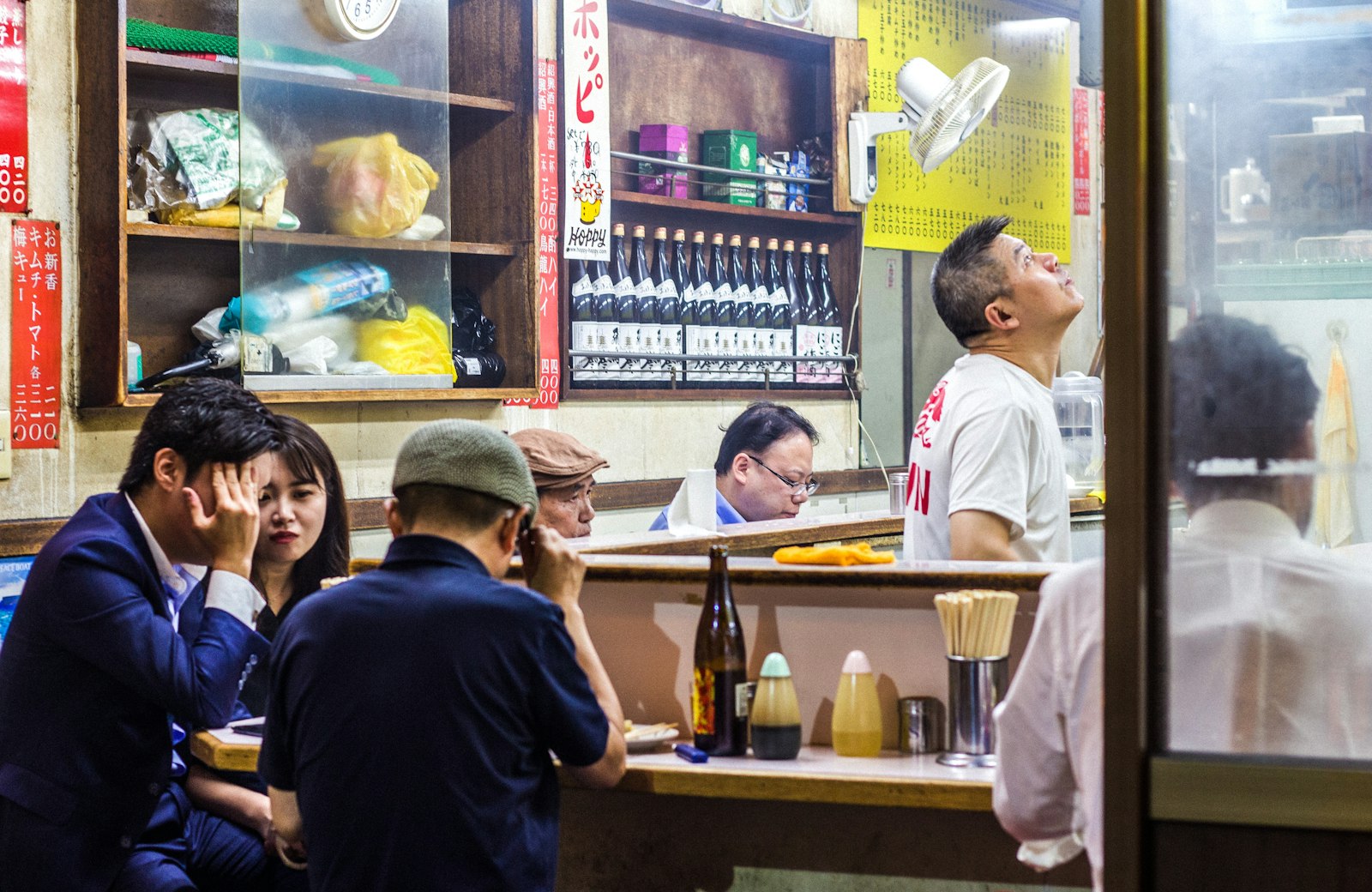 Office workers drinking at a crowded izakaya counter in Yurakucho after work