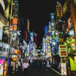 A Tokyo street at night with a convenience store, where many visitors wonder if they can drink on the street