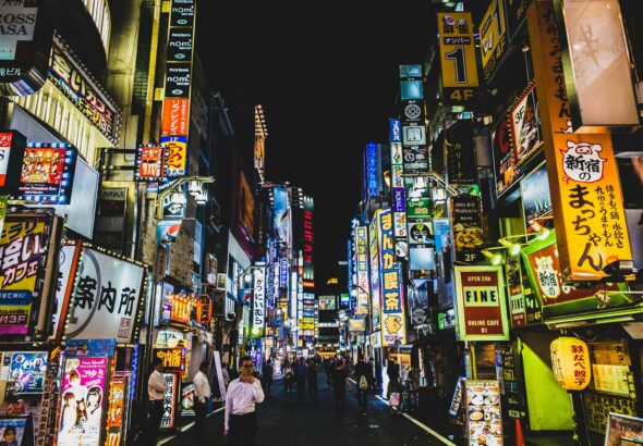 A Tokyo street at night with a convenience store, where many visitors wonder if they can drink on the street