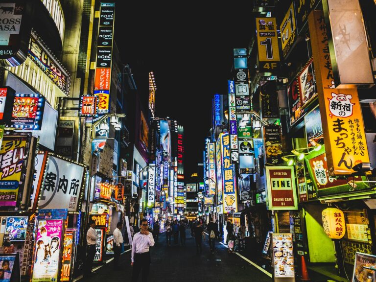 A Tokyo street at night with a convenience store, where many visitors wonder if they can drink on the street