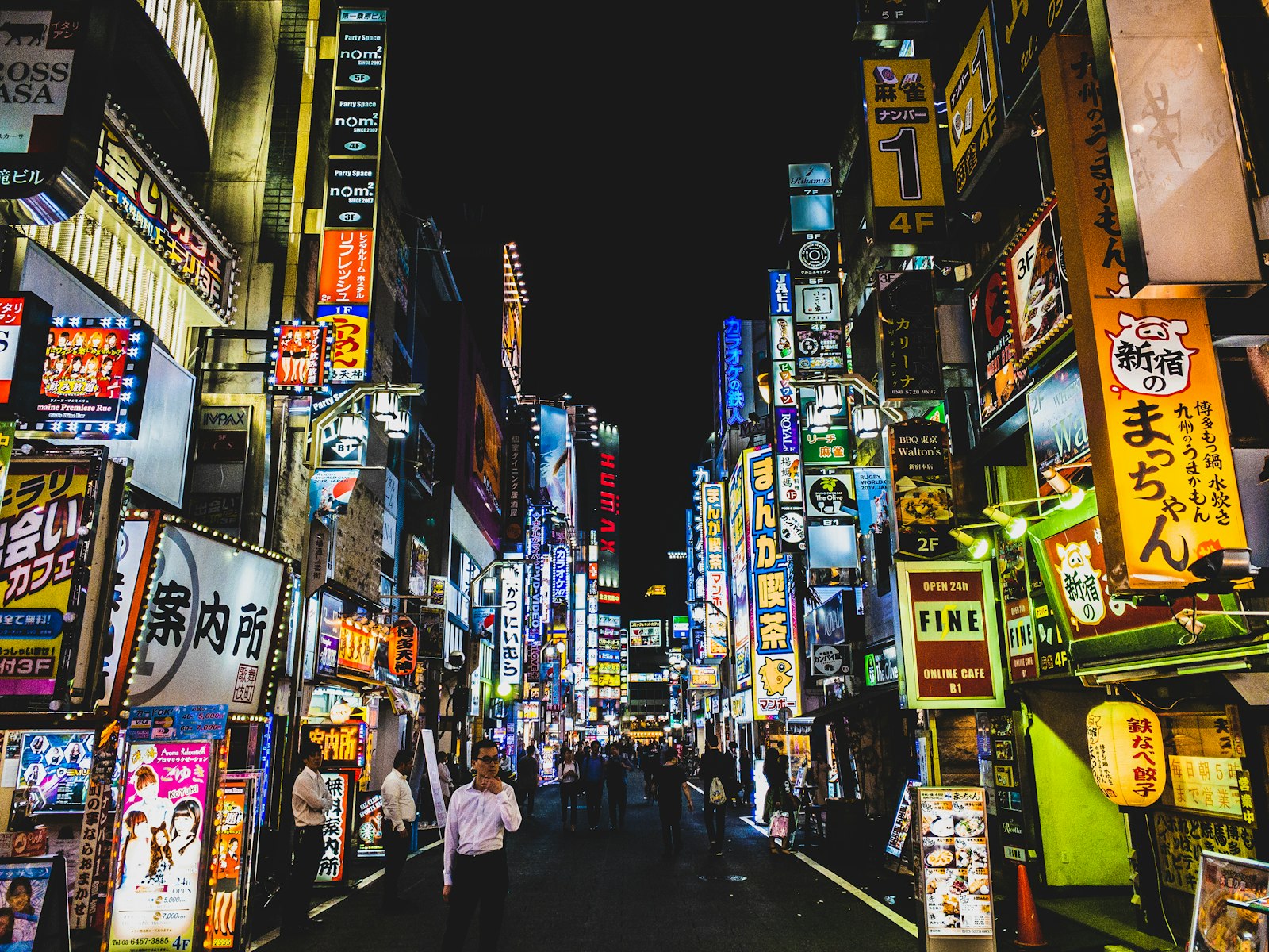 A Tokyo street at night with a convenience store, where many visitors wonder if they can drink on the street
