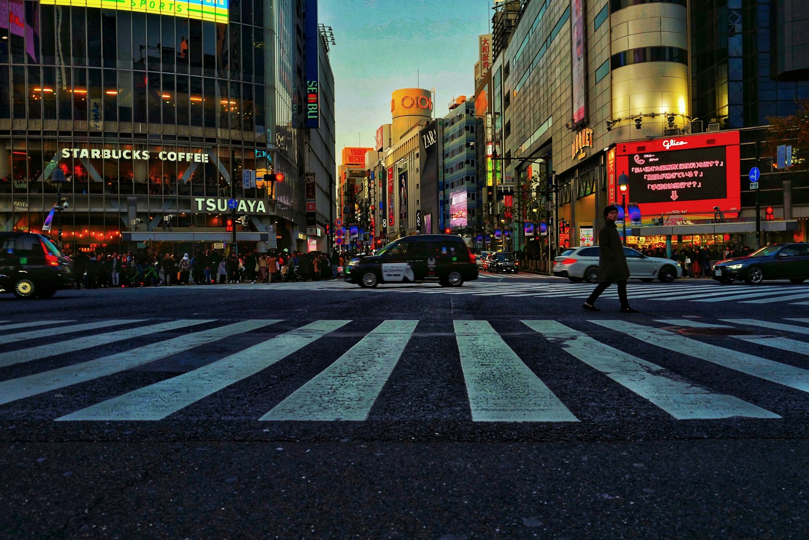 Shibuya Crossing lit up at night with few pedestrians