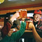 Friends raising beer glasses for a kanpai toast at a nomikai Japanese drinking party in a Tokyo izakaya