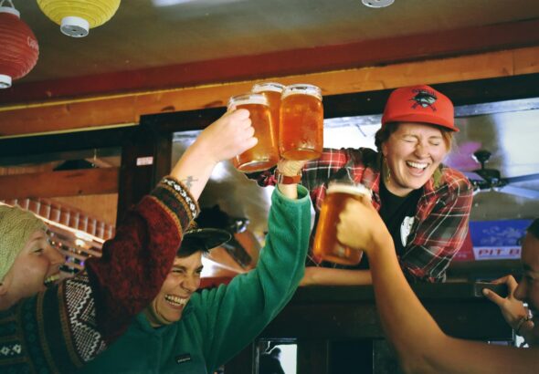 Friends raising beer glasses for a kanpai toast at a nomikai Japanese drinking party in a Tokyo izakaya