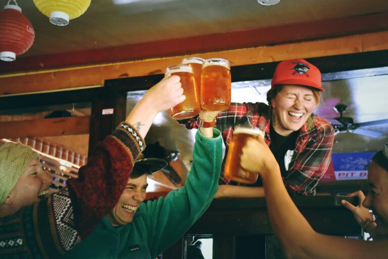 Friends raising beer glasses for a kanpai toast at a nomikai Japanese drinking party in a Tokyo izakaya