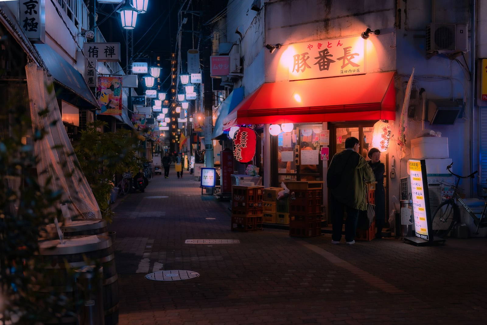 Red lanterns over a narrow Tokyo yokocho alley where locals go for nijikai drinks