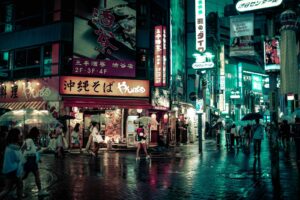 Shibuya Crossing at night with crowds crossing under glowing neon billboards and video screens