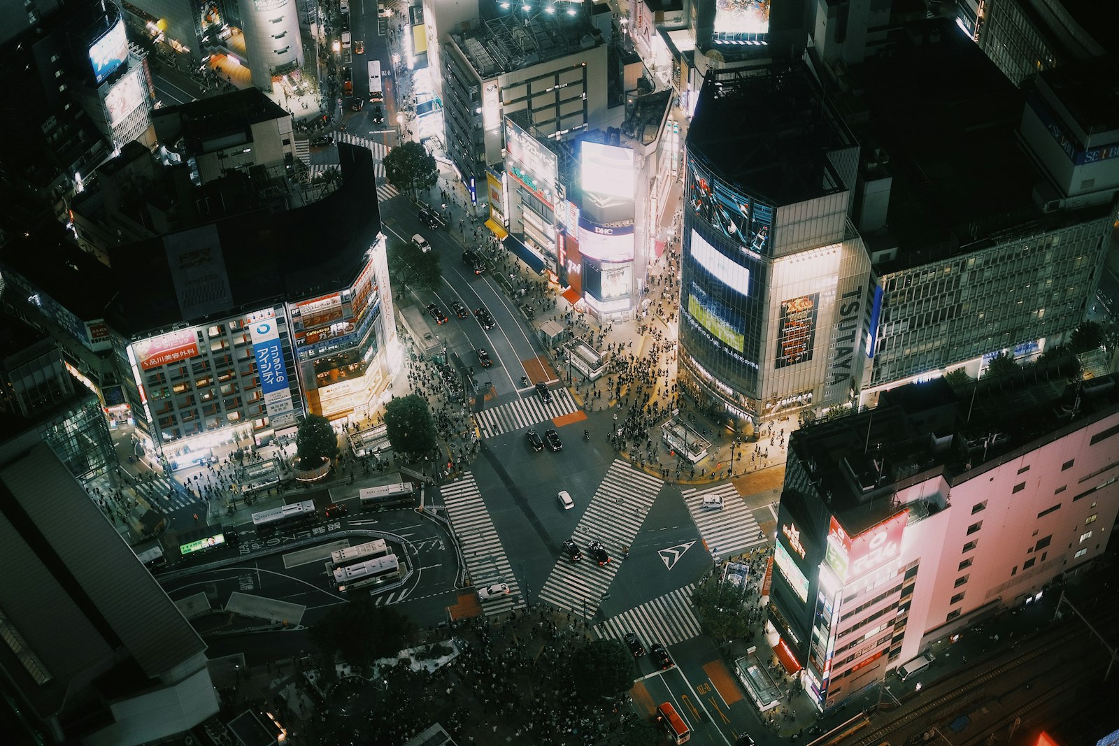 Aerial view of the Shibuya Scramble Crossing at night with people crossing in every direction