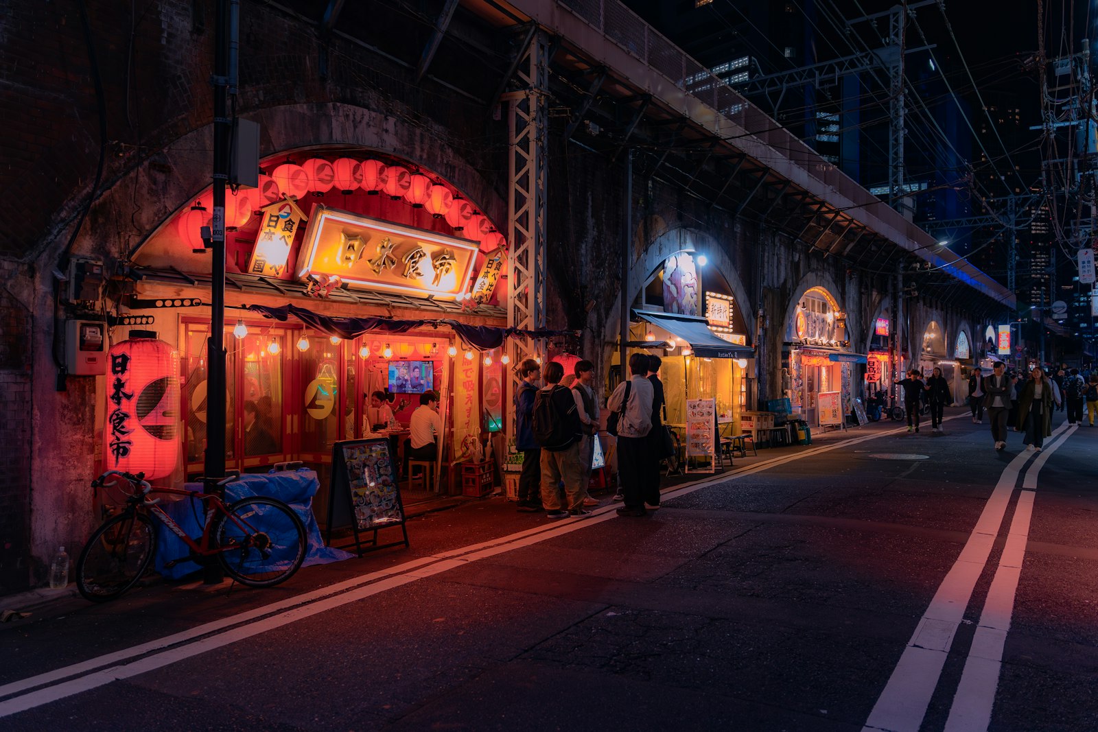 Red-brick railway arches lit up at night with small bars and restaurants underneath in Tokyo