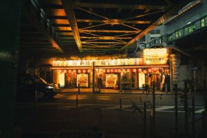 Shinbashi drinking guide: salarymen at izakaya tables under the railway tracks at night