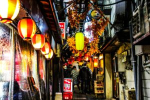 Narrow Golden Gai alley at night lit by small bar signs, a favorite stop for foreigners in Shinjuku