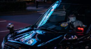 Taxis waiting on a neon-lit Shinjuku street at night, where a late-night taxi in Tokyo costs 20% more than by day