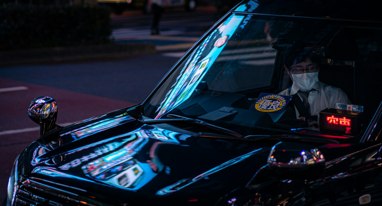 Taxis waiting on a neon-lit Shinjuku street at night, where a late-night taxi in Tokyo costs 20% more than by day