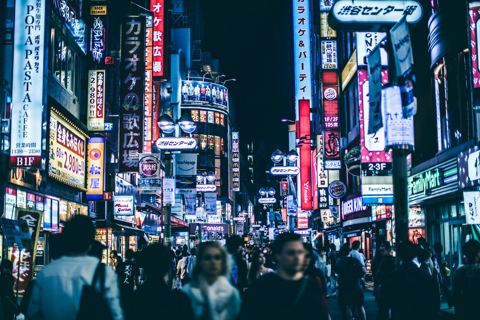 Neon-lit Shibuya street at night where many Tokyo clubs check age and ID at the door