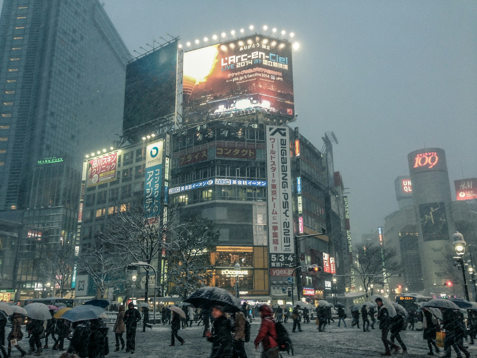 Shibuya Scramble Crossing at night with neon screens and reflections on wet pavement